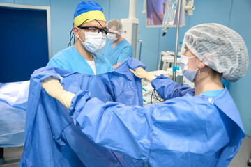 Nurse helps the doctor to put on a sterile gown