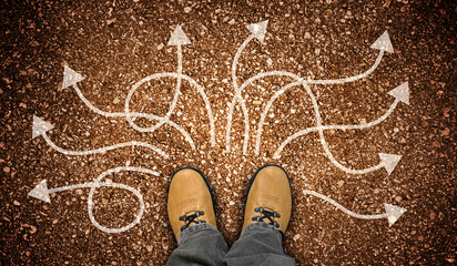 Yellow leather shoes and many winding chalky arrows on ground - decision concept