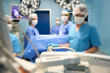 Anesthesiologist and a team of surgeons work with a patient