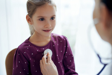 Happy smiling child girl patient at usual medical inspection. Doctor and kid patient at home. Medicine, healthcare concepts
