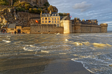 MONT SAINT-MICHEL, FRANCE, September 28, 2019 : High tide waves around the ramparts and the houses of Mont Saint-Michel Abbey.