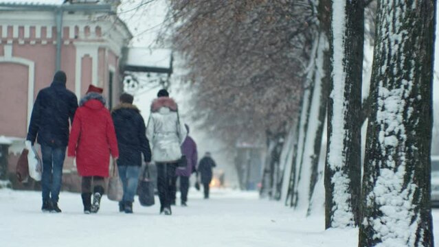 People pedestrians in a snowfall blizzard on a city street in cold winter Christmas weather