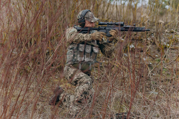 a soldier fires a machine gun. a military man in a balaclava takes aim at the enemy