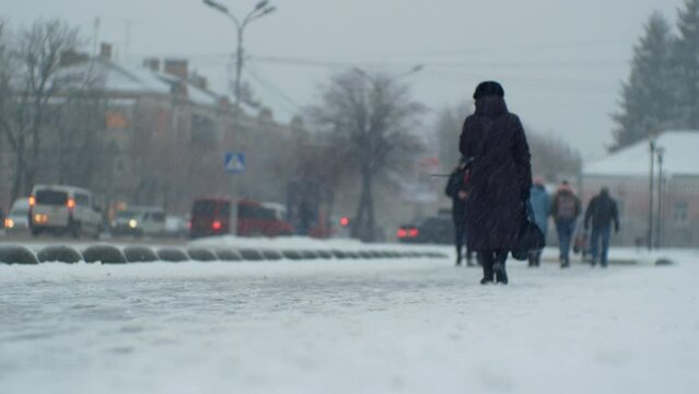 Urban people pedestrians and car traffic in a snowfall blizzard on a city street in cold windy winter Christmas weather 
