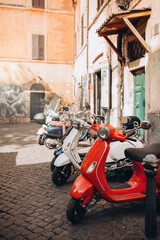 Naklejka na ściany i meble Retro vintage scooters stand near an Italian restaurant on a city street at sunny summer day.