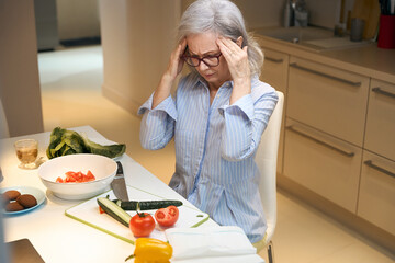 Elderly gray-haired woman suffers from a headache