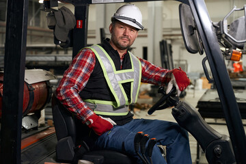 Worker sitting in loading truck and working at enterprise