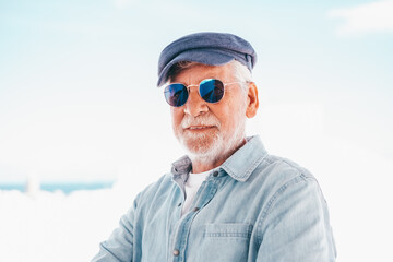 Portrait of senior man looking at camera. Face of a handsome old man wearing blue sunglasses and...