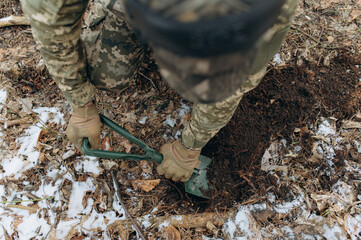 a soldier with a shovel in his hand digs the ground. an infantryman digs a hole