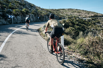 Two cyclists training on Vall d'Ebo pass.Cycling in the spanish mountains.Cyclists in helmets and cycling wear conquer Vall d'Ebo pass.Sport motivation.Cycling professional group ride.Beautiful view.