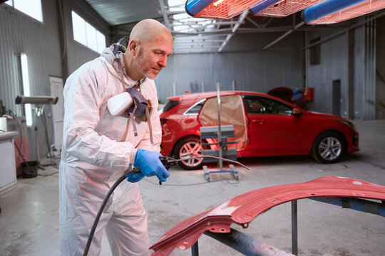 Optimistic male in work overalls picks up paint for car