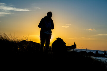 Silueta de una mujer con su perro al atardecer