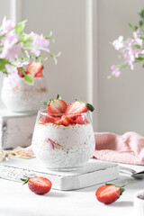 Chia pudding with strawberries and oatmeal. White background, spring pink flowers.
