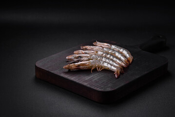 Tiger prawn or langoustine raw with spices and salt on a wooden cutting board