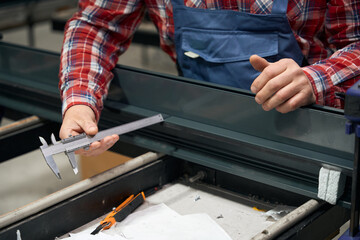 Professional man measuring metal details in factory