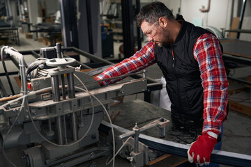 Adult man processing metal structures, manufactures products