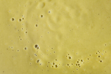 A close-up view of a delicious broccoli cream soup with vibrant green colors with bubbles on top and texture. Organic abstract background.