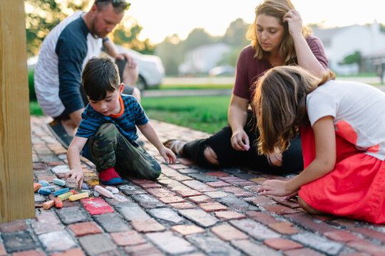Family chalks on brick sidewalk together