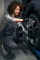 Fototapeta na wymiar Young auto mechanic performs wheel balancing, adjusts wheel alignment