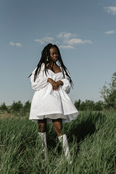 Black beautiful woman in billowing white dress on field