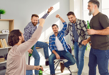 Group of happy male friends celebrating victory of favourite sport team. Hipster men meeting at...