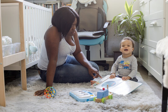 mother or nanny reading book to small child at home