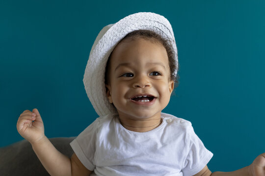 happy smiling one year old baby portrait in hat, white t-shirt