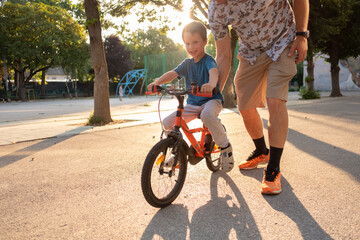 A happy boy on a bike with his father supporting him