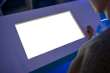 White screen, mockup, science, copyspace, template, technology concept. Woman looking at blank white display of interactive kiosk at exhibition or museum with futuristic sci-fi interior