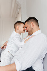 Mature father with small son sitting on sofa indoors, resting.