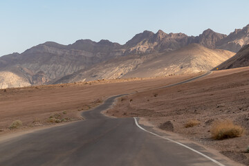 Panoramic view of endless empty road leading to colorful geology of multi hued Artist Palette rock formations in Death Valley National Park near Furnace Creek, California, USA. Black mountains