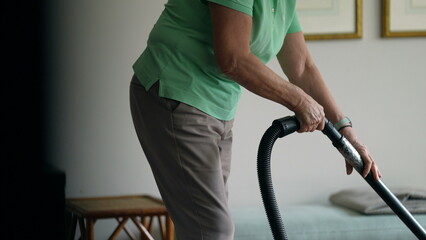 Senior woman vacuuming room. Older person cleaning household doing domestic activity at home