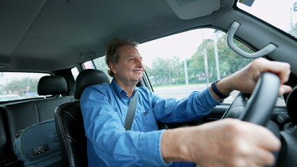 One older man driving in city in moving vehicle. Retired senior male caucasian person driver holding car steering wheel