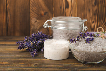 Obraz na płótnie Canvas Lavender spa. Essential oils, sea salt, handmade soap, cream and body scrub with lavender flowers on brown texture wood. Natural herbal cosmetics with flowers and lavender aroma.Aromatherapy and relax