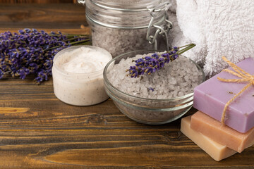 Obraz na płótnie Canvas Lavender spa. Essential oils, sea salt, handmade soap, cream and body scrub with lavender flowers on brown texture wood. Natural herbal cosmetics with flowers and lavender aroma.Aromatherapy and relax