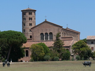 Sant'Apollinare in Classe Basilica in Ravenna, the brick facade with the circular bell tower in Byzantine style and the green lawn in front.