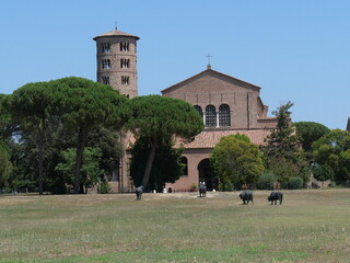 Sant'Apollinare in Classe Basilica in Ravenna, the brick facade with the circular bell tower in Byzantine style and the green lawn in front.