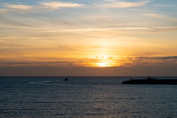 Naklejka na ściany i meble Sunset at the blue hour with a tugboat leaving the port