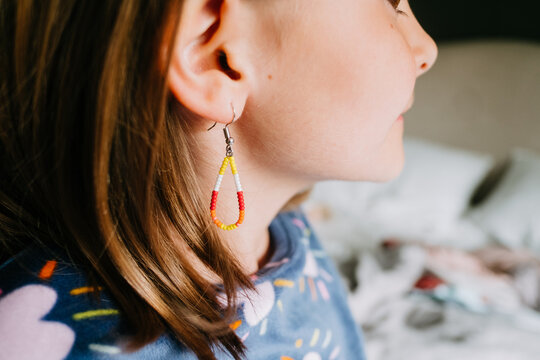 Closeup portrait of a young girl showing her beaded earrings