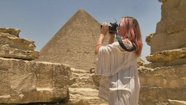 2022 - Side view of a woman taking pictures of the pyramids of Giza.