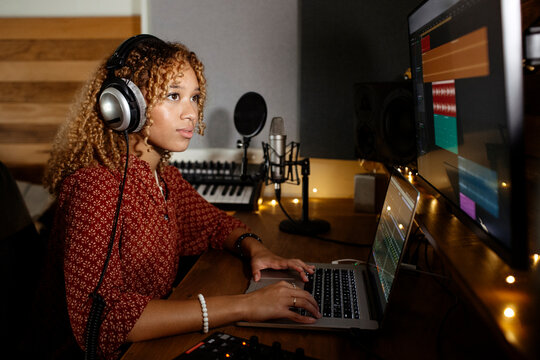 Music producer working at home studio using laptop and monitor display