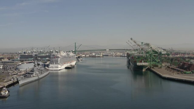 2022 - Excellent aerial footage of a luxury liner, battleship and other boats docked at a Los Angeles harbor.