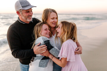 Naklejka premium Smiling family hugging at the beach