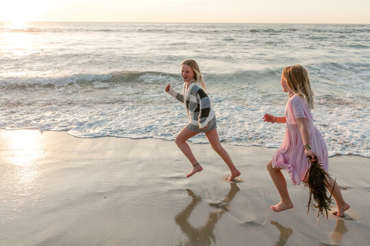 Smiling sisters running together on the beach