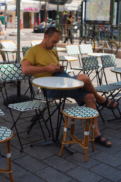 Man sitting at outdoor cafe with phone