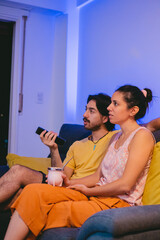 Young Argentinian couple sharing a mate while watching what's on TV. Vertical photo.