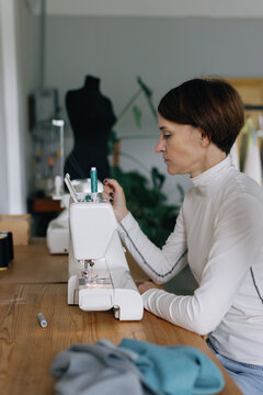Textile machine. Focused on task. Professional modiste. Craft