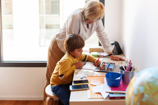 Grandma with her grandchild while drawing at desk