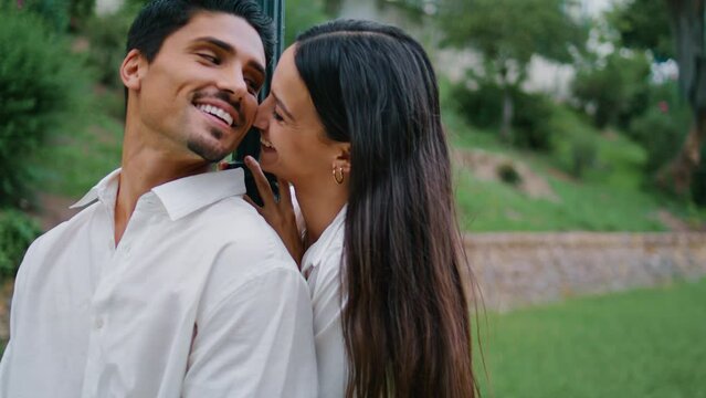 Affectionate spouses flirting at park close up. Playful woman kissing husband