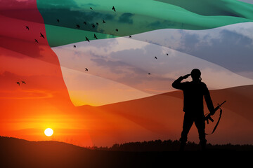 Silhouette of soldier saluting on background of UAE flag and the sunset or the sunrise. Commemoration Day.